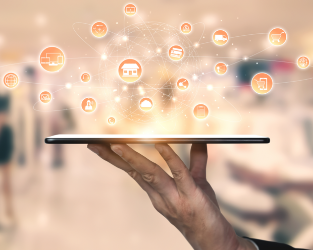 Tablet mit schwebenden digitalen Symbolen für E-Commerce, Kommunikation und Cloud-Technologien in einer vernetzten Welt