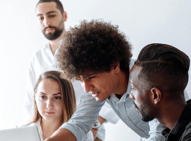 Four-person team working focused around a laptop